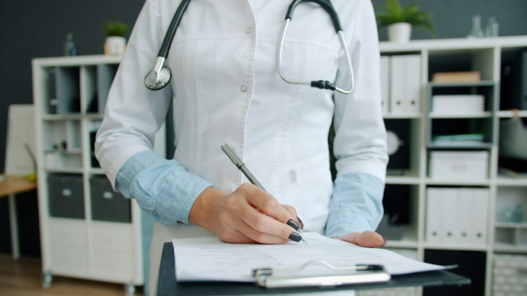 Doctor filling out paperwork on a clipboard